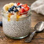 easy chia seed pudding recipe served in a mason jar with strawberries blueberries banana slices and coconut flakes